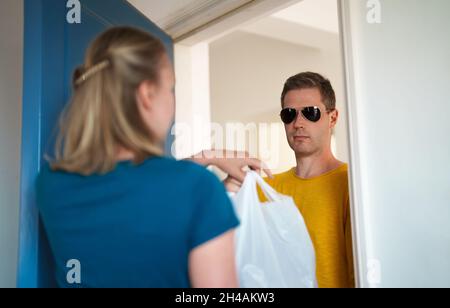 L'homme livre le paquet à la femme.Service de livraison de nourriture. Banque D'Images