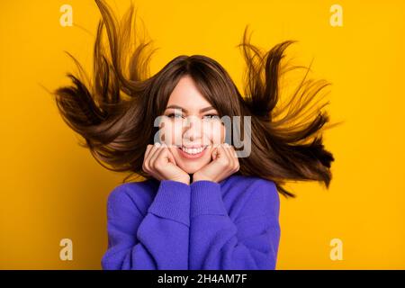 Photo de douce jolie jeune femme vêtue violet chandail vent soufflant cheveux bras joues isolé couleur jaune fond Banque D'Images