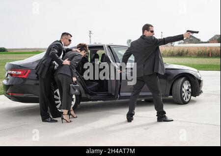 Une équipe armée professionnelle de gardes du corps féminins et masculins protège la personne célébrité en limousine de voiture.BodyGuard et protection de sécurité VIP.Profess Banque D'Images