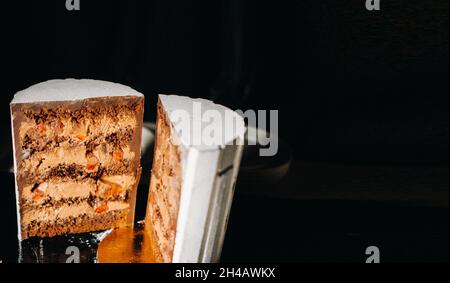 Des gâteaux incroyables.Gâteau de mariage en tranches de chocolat avec garniture étonnante sur fond noir. Grand gâteau au chocolat blanc. Banque D'Images