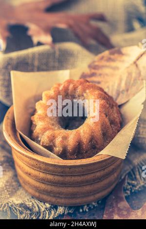 Mini-petit gâteau, guglhupf, muffin dans un bol rustique avec feuilles d'automne, gros plan, vertical Banque D'Images