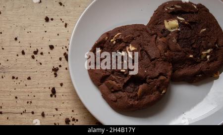Double biscuits aux pépites de chocolat sur une assiette avec des miettes éparpillées Banque D'Images