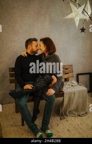 Joyeux couple hispanique dans un studio moderne décoré sur le thème de Noël Banque D'Images