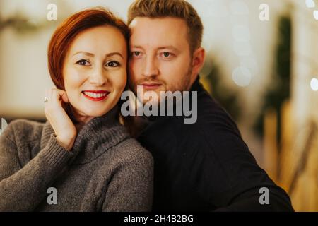 Joyeux couple hispanique dans un studio moderne décoré sur le thème de Noël Banque D'Images