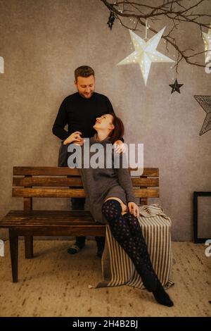 Joyeux couple hispanique dans un studio moderne décoré sur le thème de Noël Banque D'Images