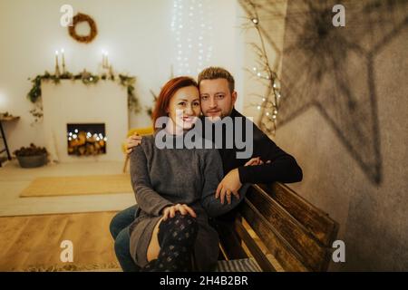 Joyeux couple hispanique dans un studio moderne décoré sur le thème de Noël Banque D'Images