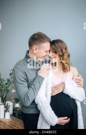 L'homme embrasse sa femme enceinte. Elle épouse son sourire. Banque D'Images