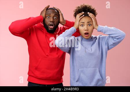 Choqué inquiet africain américain couple homme femme tenant les mains tête paniquant élargir les yeux stupéfaits recevoir mauvais concernant les nouvelles se sentent troublés nerveux Banque D'Images