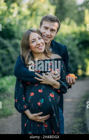 Concept couple marié est enceinte.Portrait de la femme, de la future mère et de l'homme père, embrassant le gros ventre.Les gens du milieu plan regarder la caméra, ve Banque D'Images