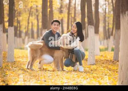 Les jeunes amoureux et leur chien de compagnie jouant dans les bois en automne Banque D'Images