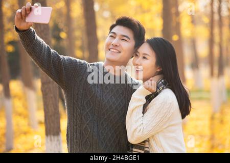 Un jeune couple heureux qui prend des selfies avec son téléphone portable Banque D'Images