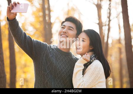 Un jeune couple heureux qui prend des selfies avec son téléphone portable Banque D'Images