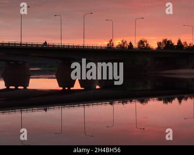 Vue latérale sur le pont sur un fond de rivière d'un coucher de soleil violet. Banque D'Images