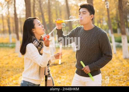 Joyeux jeune couple qui soufflait de bulles Banque D'Images