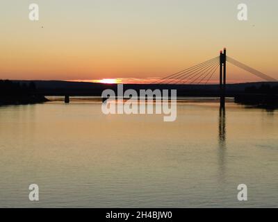 Vue latérale sur le pont sur un fond de rivière d'un coucher de soleil violet. Banque D'Images