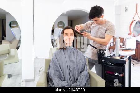 Jeune gars professionnel coiffeur coupe les cheveux de femme Banque D'Images