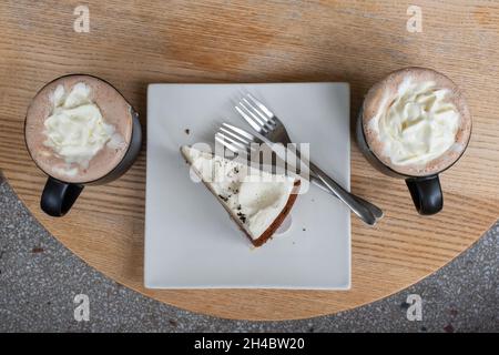 Deux tasses de moka et une tranche de gâteau au chocolat dans une assiette sur une table en bois Banque D'Images