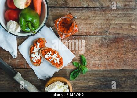 Pain complet recouvert de sauce tomate-poivre et de fromage feta sur une ancienne table rustique en bois.Plat de légumes bio fait maison. Banque D'Images