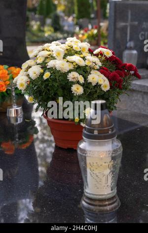 Fleurs colorées et une lumière grave sur une pierre tombale de granit. Banque D'Images