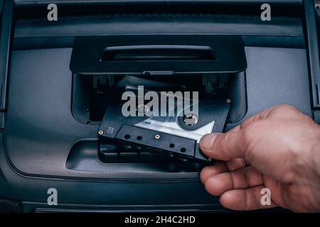 man place une cassette dans un magnétophone sur fond noir Banque D'Images