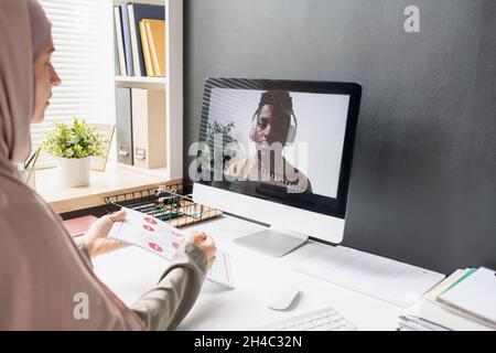 Jeune étudiant africain dans des écouteurs sur écran d'ordinateur à l'écoute des explications des enseignants pendant la leçon en ligne Banque D'Images