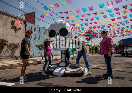 Mexiko Stadt, Mexique.1er novembre 2021.Les gens placent une grande réplique d'un crâne dans une rue du quartier de Tláhuac pour célébrer le jour des morts.Avec ses offrandes, bougies, maquillage et sculptures, des milliers de Mexicains à travers le pays célèbrent le jour des morts.Credit: Jair Cabrera Torres/dpa/Alay Live News Banque D'Images