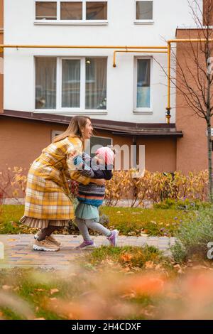 Mère jouant avec sa fille dans la rue d'automne.Couleurs d'automne Banque D'Images