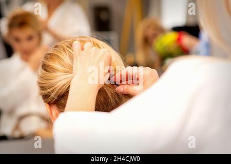 Mains de styliste de cheveux faisant la coiffure professionnelle des cheveux longs de femme dans un salon de beauté Banque D'Images