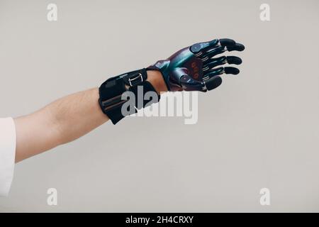 Homme handicapé avec une main prothétique artificielle gros plan de la main mâle sur fond gris Banque D'Images