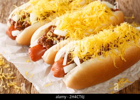 Hot dog de piment de Cincinnati avec saucisse de bœuf, cheddar et oignons gros plan sur un fond en bois ancien. Horizontal Banque D'Images