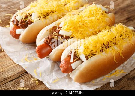 Chien chaud au Chili de Cincinnati avec saucisse de bœuf, cheddar et oignons en gros plan sur le papier de la table.Horizontale Banque D'Images