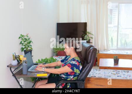 Femme latine assise au bureau et regardant un ordinateur portable.Jungle urbaine Banque D'Images