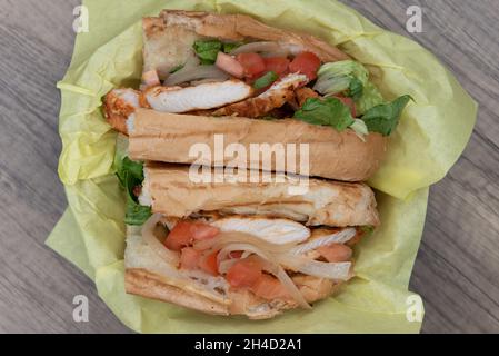 Vue en hauteur d'un sous-sandwich au poulet Tikka chargé avec des garnitures dans un petit pain fraîchement cuit. Banque D'Images