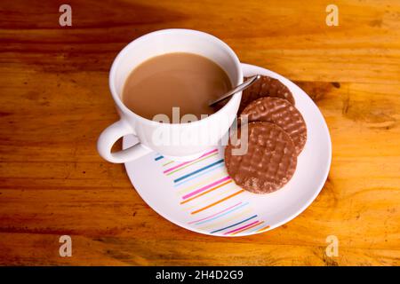 Tasse de thé et biscuits, friandises au chocolat McVités sur table Banque D'Images