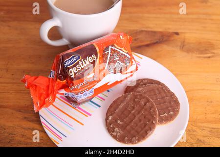 Assiette de biscuits digestifs au chocolat McVités avec sachet ouvert et tasse de thé Banque D'Images