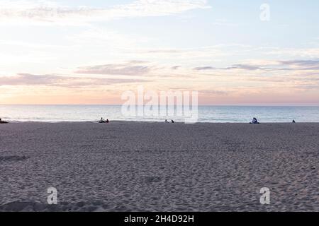 Sonnenuntergang am Strand von Espinho.Paare sitzen am Strand, nicht zu erkennen und schauen sich den Sonnenuntergang an Banque D'Images