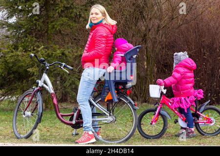 Enfant sur le siège de vélo femme sur vélo et deux enfants Banque D'Images