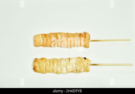 graissonnage de la graisse de saumon grillée dans un bâton de bois sur fond blanc Banque D'Images