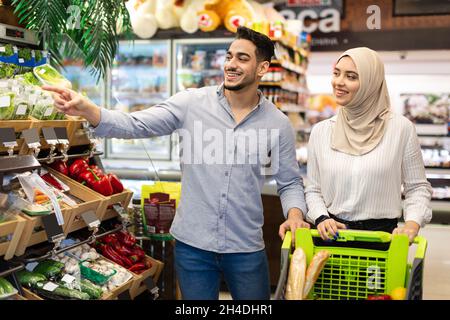 Couple islamique faire des courses en pointant du doigt choisir de la nourriture dans un supermarché Banque D'Images