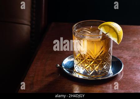 Cocktail de whisky et de soda sur les rochers avec coin de citron dans le bar de luxe sombre Banque D'Images