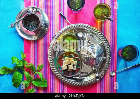 Deux verres de thé chaud à la menthe marocaine sur un plateau métallique avec un thé, de la menthe et des cubes de sucre brun Banque D'Images