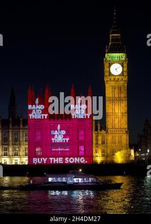 La vidéo de Band Aid 30, « est-ce que c'est Noël ? », est projetée pour la première fois sur les chambres du Parlement.Il marque la copie papier du CD en vente demain matin (08/12/14).la chanson présente des artistes dont One Direction, Ellie Goulding, Emeli SandŽ et Ed Sheeran, entre autres. Banque D'Images