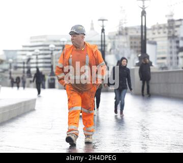 Des gens sont pris dans une tempête de grêle à Southbank près de Tower Bridge, Londres, le mardi 26 avril.Le Royaume-Uni doit faire face à une course à froid record jusqu'en mai avec des températures glaciales et des prévisions de neige pour les 10 prochains jours. Banque D'Images