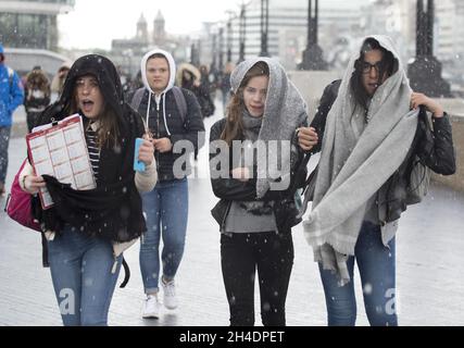 Des gens sont pris dans une tempête de grêle à Southbank près de Tower Bridge, Londres, le mardi 26 avril.Le Royaume-Uni doit faire face à une course à froid record jusqu'en mai avec des températures glaciales et des prévisions de neige pour les 10 prochains jours. Banque D'Images