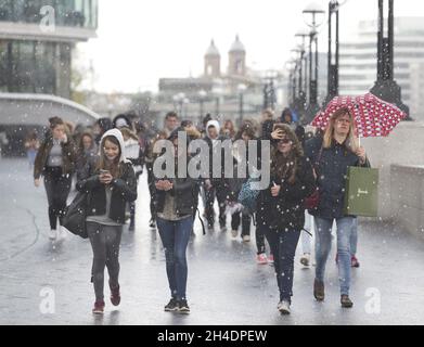 Des gens sont pris dans une tempête de grêle à Southbank près de Tower Bridge, Londres, le mardi 26 avril.Le Royaume-Uni doit faire face à une course à froid record jusqu'en mai avec des températures glaciales et des prévisions de neige pour les 10 prochains jours. Banque D'Images