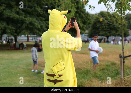 Un fan de Pokemon habillé comme personnage préféré Pikachu joue Pokemon Go sur son téléphone à Hyde Park, dans le centre de Londres, le samedi 30 juillet. Banque D'Images