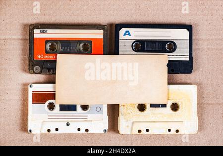 Quatre anciennes cassettes audio et du papier vide sur le carton gros plan Banque D'Images