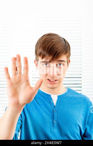 Un jeune homme sérieux montre un geste de refus sur le fond de Jalousie dans une salle Banque D'Images