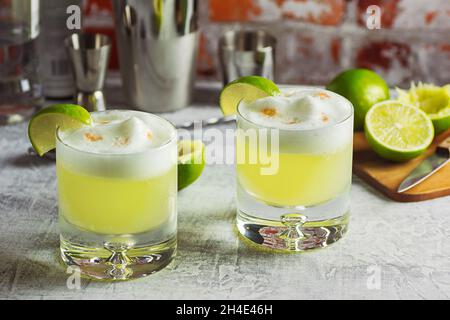 Cocktails Pisco sour avec mousse blanche de citron vert et d'oeuf sur le dessus de bar avec des outils Banque D'Images