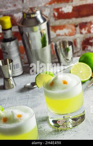 Cocktails Pisco sour avec mousse blanche de citron vert et d'oeuf sur le dessus de bar avec des outils Banque D'Images